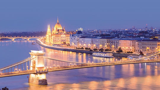 A view over the Danube river in Budapest at night, with the Parliament Building and Chain Bridge illuminated, Hungary